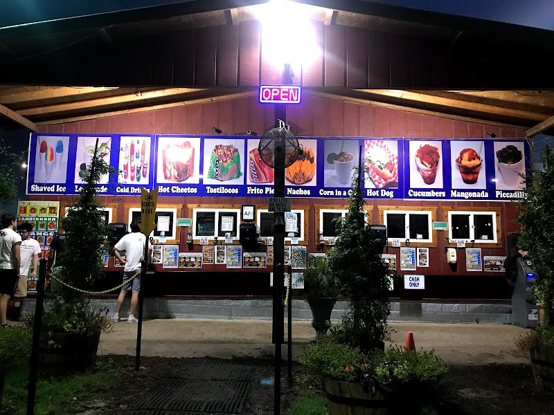 The Gorilla Shaved Ice stand lit up at night with the full menu board