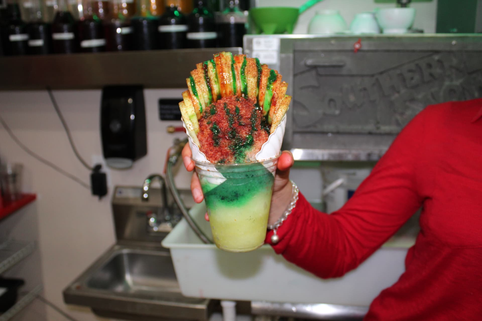 Chamoyada cup with chile cucumber spears held at the counter