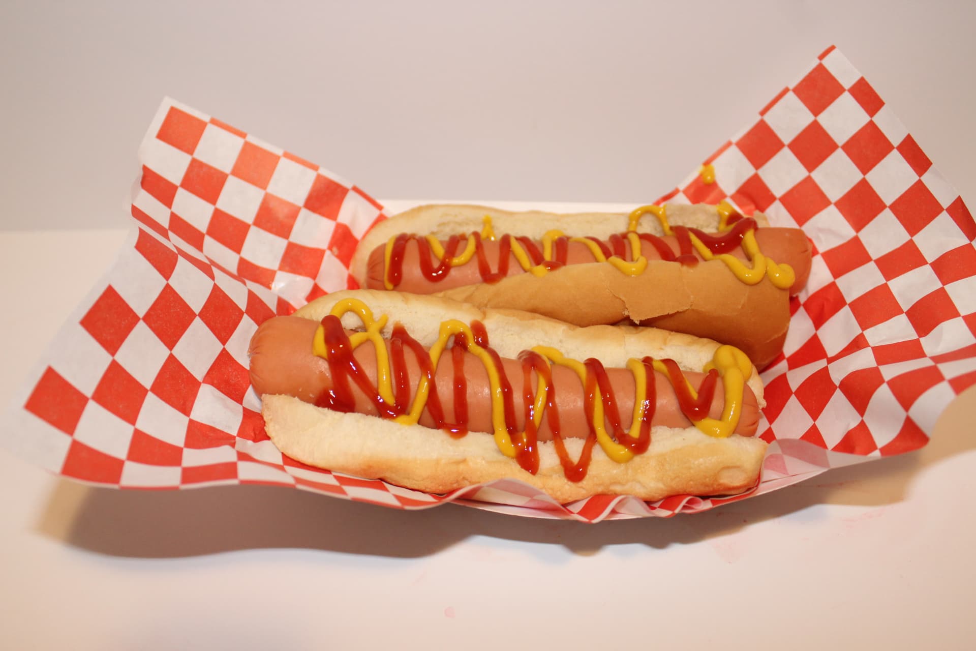 Two hot dogs with ketchup and mustard in a checkered basket