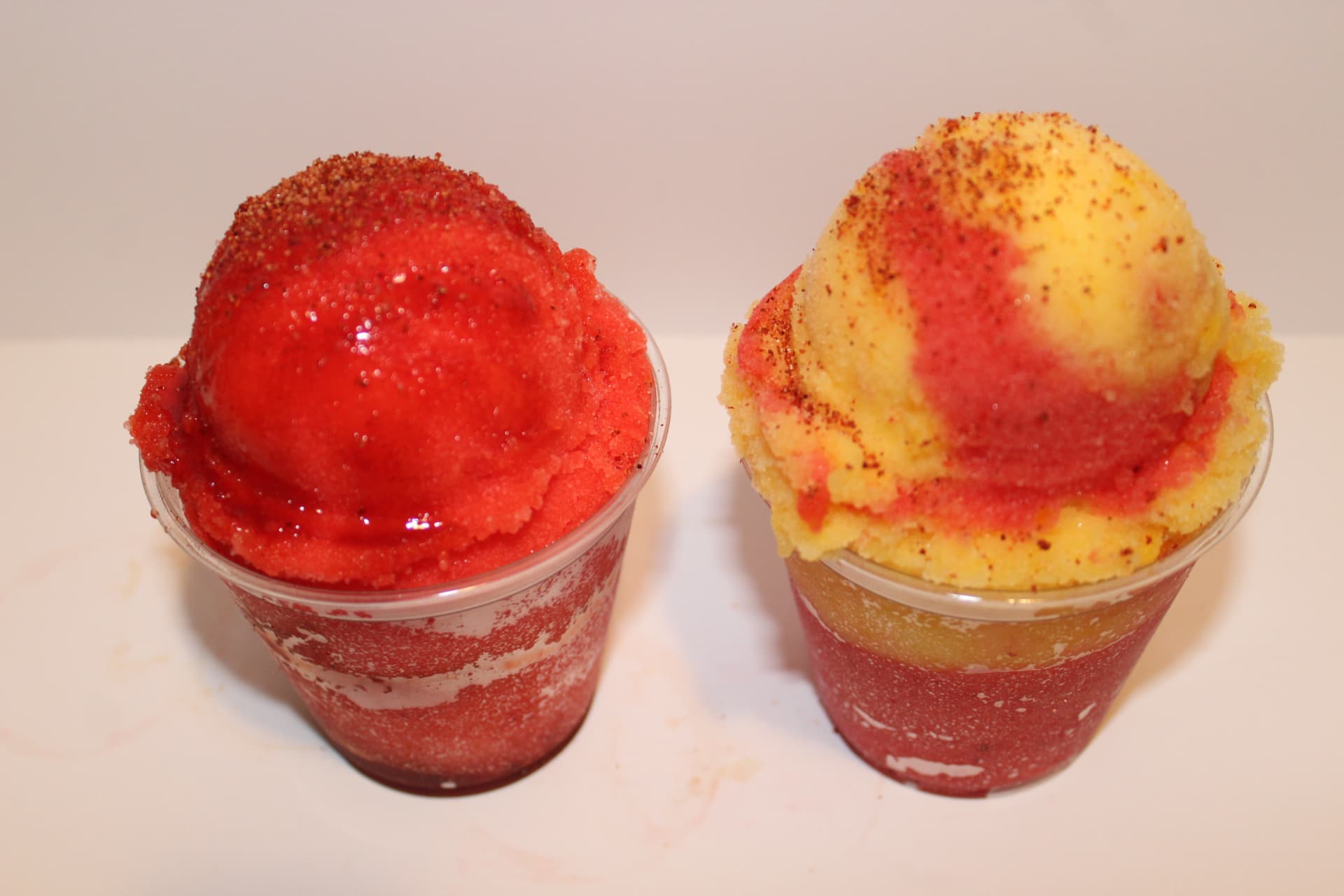 Two mangonada cups topped with chamoy and Lucas